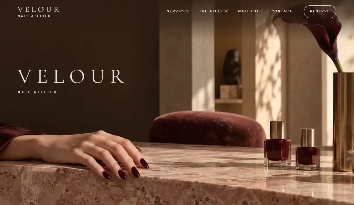A hand with burgundy nails resting on a rose marble counter beside two bottles of polish
